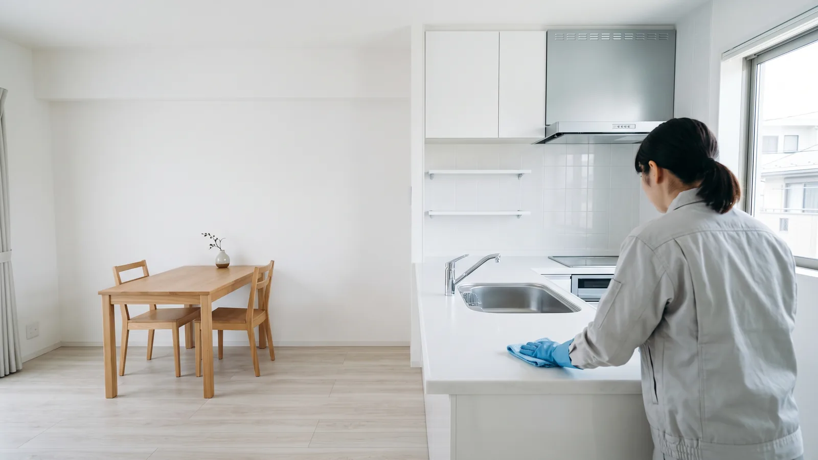 イメージ:掃除を終えたマンションのキッチンで、作業員が布で調理台を拭いている後ろ姿